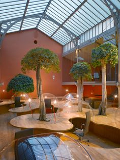 the inside of a building with tables and trees in it's centerpieces