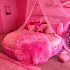 a pink room with a bed, rugs and pillows on the floor in front of it