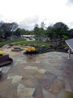 a stone patio with benches and flowers on it