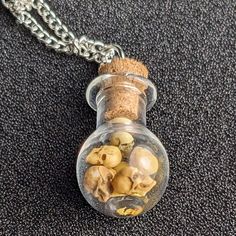 a glass bottle filled with skulls and bones on a chain