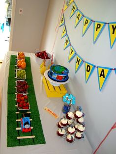 a table topped with cupcakes and cakes covered in frosting next to a train