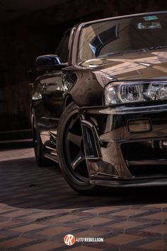 the front end of a black car parked on top of a checkered tile floor