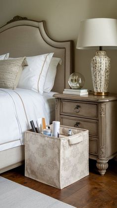 a white bed sitting next to a nightstand with a lamp on top of it