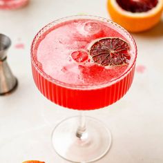 a blood orange margarita garnished with grapefruit and an orange slice on the rim