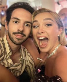 a man and woman taking a selfie in front of a crowd at a party