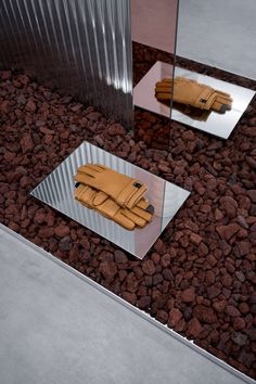 a pair of brown gloves sitting on top of a glass table next to a mirror