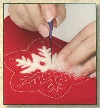 someone is cutting out snowflakes on a red paper with a blue plastic needle