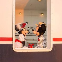 two mickey and minnie mouses in front of a mirror on the side of a train