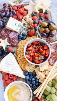 an assortment of cheeses, crackers and fruit on a platter