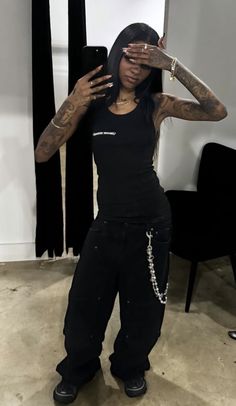 a woman with tattoos holding her hands up to her face while standing in front of a mirror