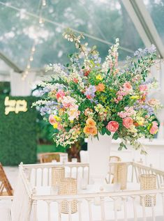 a vase filled with flowers sitting on top of a white table under a tented area