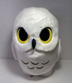 a white stuffed owl with yellow eyes and black beak sitting on top of a table