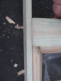 a person holding a piece of wood in front of an open window with the door frame missing