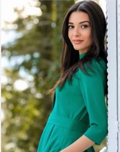 a woman in a green dress leaning against a wall