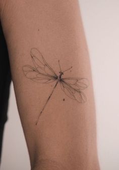 a small dragonfly tattoo on the arm