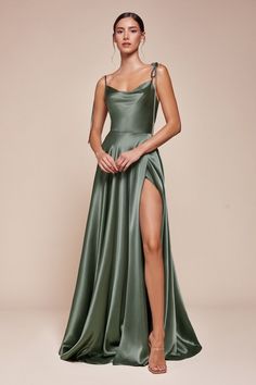 A woman stands confidently in a flowing green satin dress with a high slit, showcasing her leg. The backdrop is a soft beige, enhancing the elegance of the outfit. Silky Dresses Long, Bridesmaid Dress Styles Satin, Green Elegant Dresses, Silky Dress Long, Bridesmaid Dress Satin, Romantic Gown, Simple Satin, Shirt Jacket Men, Cinderella Divine