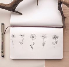 an open notebook with flowers drawn on it next to a pen and some paper clips