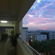 a balcony overlooking the city at dusk with pink and blue clouds in the sky above