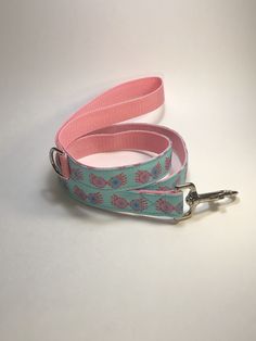 a pink and blue leash with flowers on it, sitting on a white surface next to a pair of scissors