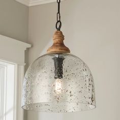 a glass light fixture hanging from a ceiling in a room with white walls and windows