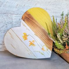 a wooden heart with flowers on it next to a potted plant in the shape of a heart