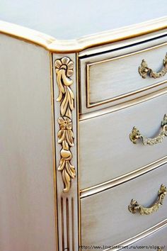 a white and gold painted dresser with ornate handles