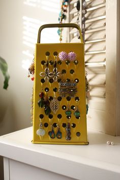 a gold purse with lots of earrings hanging from it's sides on a white shelf