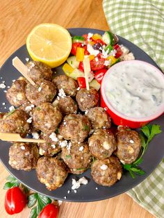 a plate with meatballs and vegetables on it next to a bowl of dip sauce