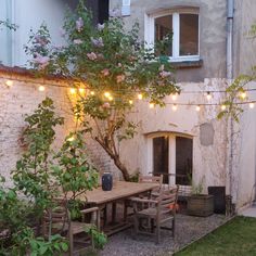 an outdoor dining area with patio furniture and string lights strung from the side of a building