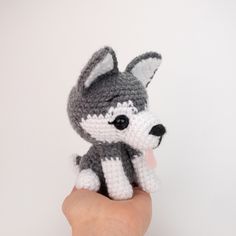 a small crocheted stuffed animal sitting on top of a persons hand in front of a white wall