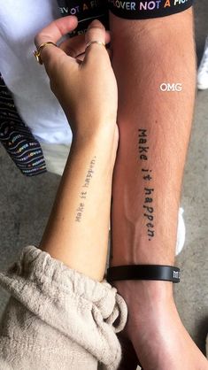 two people with tattoos on their arms holding each other's hands and writing on the arm