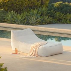 a white lounge chair sitting on top of a cement floor next to a swimming pool