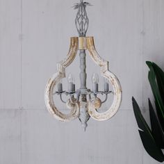 an old chandelier hanging from the ceiling in front of a white painted wall