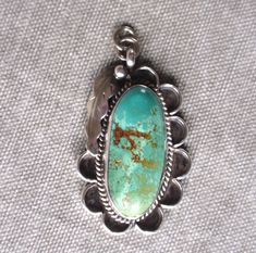 Gorgeous early 80s vintage Navajo turquoise and sterling silver pendant with deep, carved scalloped edges is accented with rope and traditional feather trim. This stone with its strong coloration of blue, green and deep rust also has bits of robin's egg blue. It was likely mined in Nevada's famous Royston mining region. This pendant was my mother's, and she bought it for the beautiful, unusual stone and deeply carved setting. It has been treasured, but rarely worn and carefully stored. It's unus Bohemian Untreated Oval Turquoise Necklace, Untreated Oval Turquoise Necklace In Bohemian Style, Vintage Turquoise Engraved Jewelry, Vintage Engraved Turquoise Jewelry, Antique Turquoise Jewelry With Patina, Antique Untreated Turquoise Jewelry, Collector's Turquoise Necklace With Round Pendant, Vintage Patina Pendant Jewelry, Collectible Turquoise Jewelry With Patina