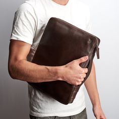 a man holding a brown leather case in his hands