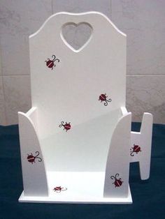 a white chair with red ladybugs painted on the front and back sides, sitting on a blue table cloth