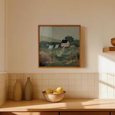 a bowl of fruit sitting on top of a wooden counter next to a painting hanging above it