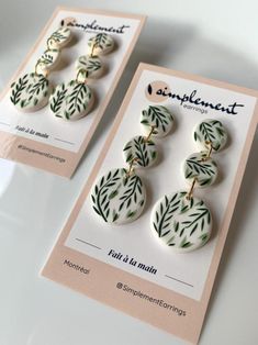 two white and green earrings on top of a card with the words complimentent written below them