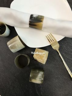 a white plate topped with two forks next to cups and saucers on top of a table