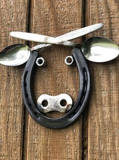 a cow head made out of spoons on top of a wooden surface with scissors attached to it