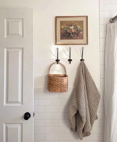 a bathroom with white tile walls and black hooks on the wall next to a towel rack