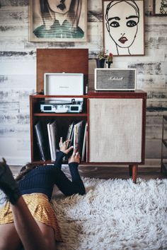 a woman laying on the floor in front of a radio and record player with her legs crossed