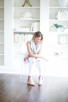 a woman sitting on a chair in front of a bookshelf