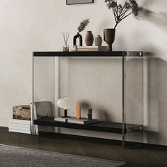 a shelf with vases and other items on it in front of a white wall