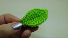 a hand holding a green crochet leaf