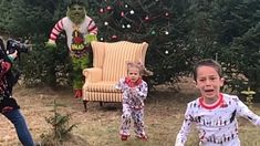 two children are playing in the yard with an alien doll and fake christmas tree behind them