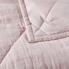 an unmade bed with pink linens and white sheets on top of each other