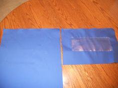 two pieces of blue paper sitting on top of a wooden floor next to a piece of plastic