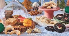 a table topped with lots of different types of desserts and pastries on top of snow covered ground