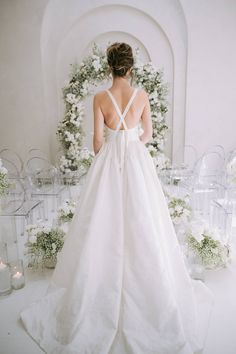 a woman in a white wedding dress standing next to flowers and glass vases with candles